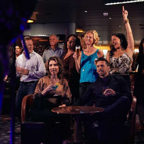 A crowd in a bar watching a guitarist on stage