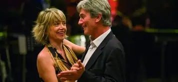 Image related to An older couple dancing, the man wearing a shirt and suit jacket