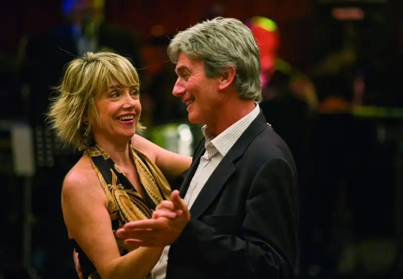 An older couple dancing, the man wearing a shirt and suit jacket