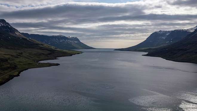 Sail into a stunning eastern fjord lined with waterfalls and a colourful artists' town.