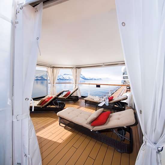 Several sun loungers in a private cabana space on a cruise ship's top deck