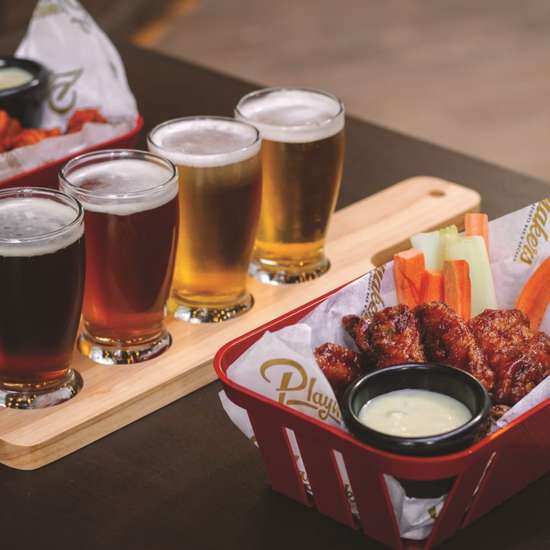 Chicken wings and a beer flight on a table