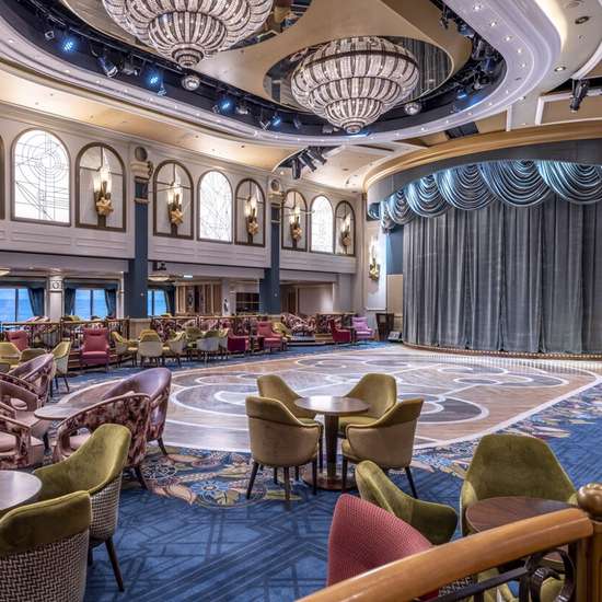 An elegant dance floor surrounded by tables and chairs, with a stage at one end.