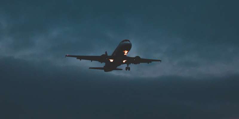 A plane flying at night in a cloudy sky