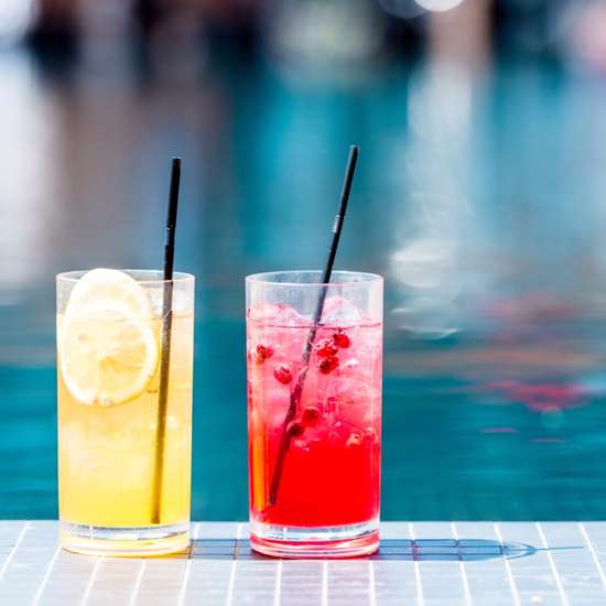 Cose-up shot of glasses of red and orange cocktails poolside
