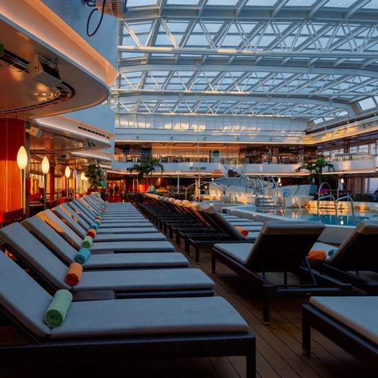 A row of sun loungers beside a pool under a domed glass roof