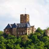 A medieval castle protruding from vibrant green trees