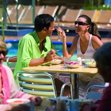 Image related to A younger couple enjoying breakfast outside, overlooking a pool area