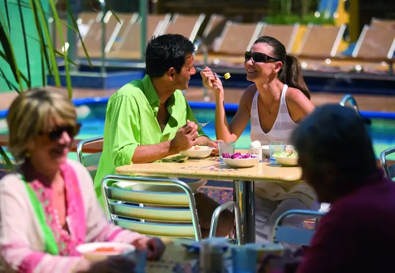 A younger couple enjoying breakfast outside, overlooking a pool area