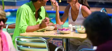 Image related to A younger couple enjoying breakfast outside, overlooking a pool area