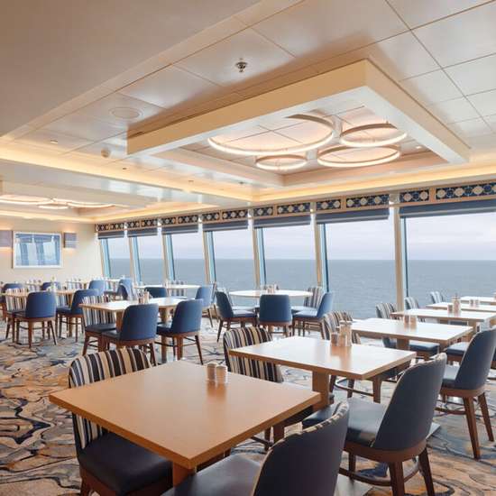 A bright restaurant on a cruise ship with blue chairs and a wall of windows