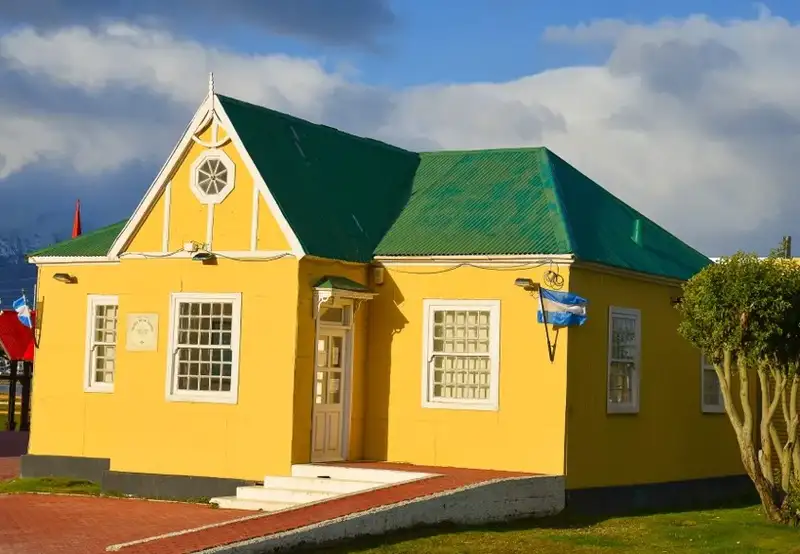 A yellow house with a green roof in the sunshine