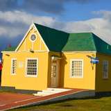 A yellow house with a green roof in the sunshine