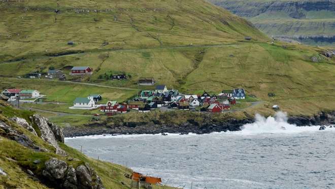 Discover a tiny, turf-roofed Faroese village nestled between mountains and the sea.