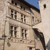 A carved stone wall with windows of a medieval building in Viviers, France