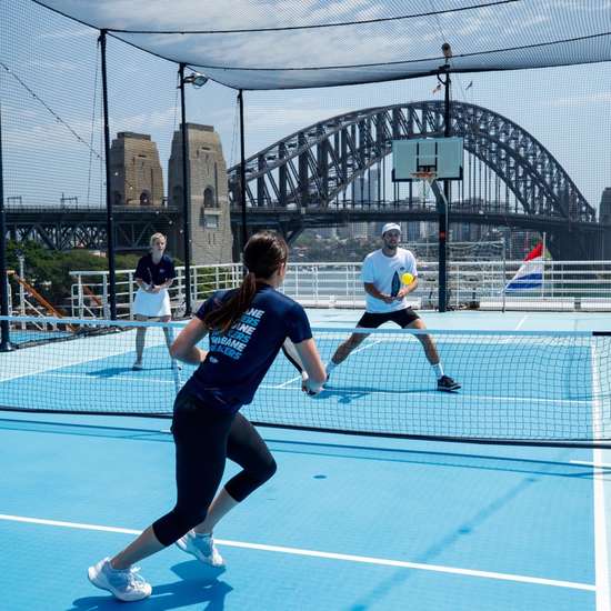Two couples playing pickleball on the top deck of a cruise ship