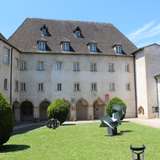 An image of a courtyard with grass and sculpted green bushes