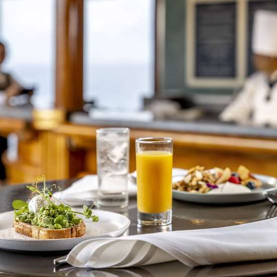 Two healthy meals on a table, one with water, one with orange juice