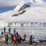 A group of tourists looking at glacier from the shore
