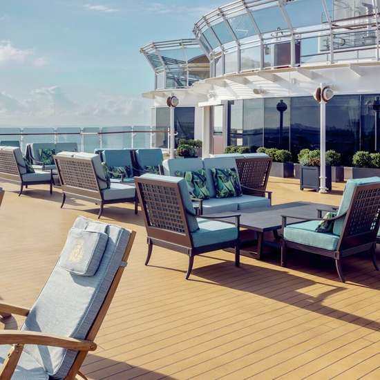 Sun loungers and chairs outside on a wooden deck.