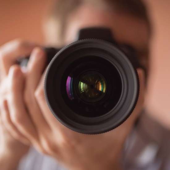Looking down the lens of someone taking a photo with a camera