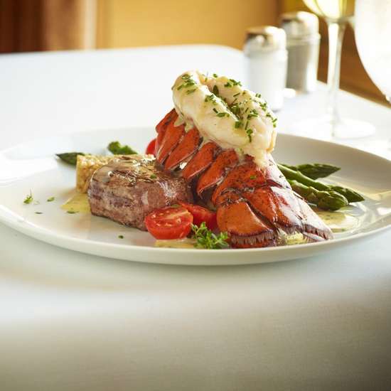 A fine dining lobster dish on a table covered by a white tablecloth