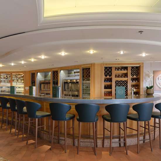 Blue chairs along a curved bar with bottles of wine behind the counter