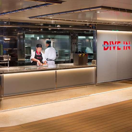 The counter for the Dive-In grill, mostly silver-coloured metal, with two chefs working behind it